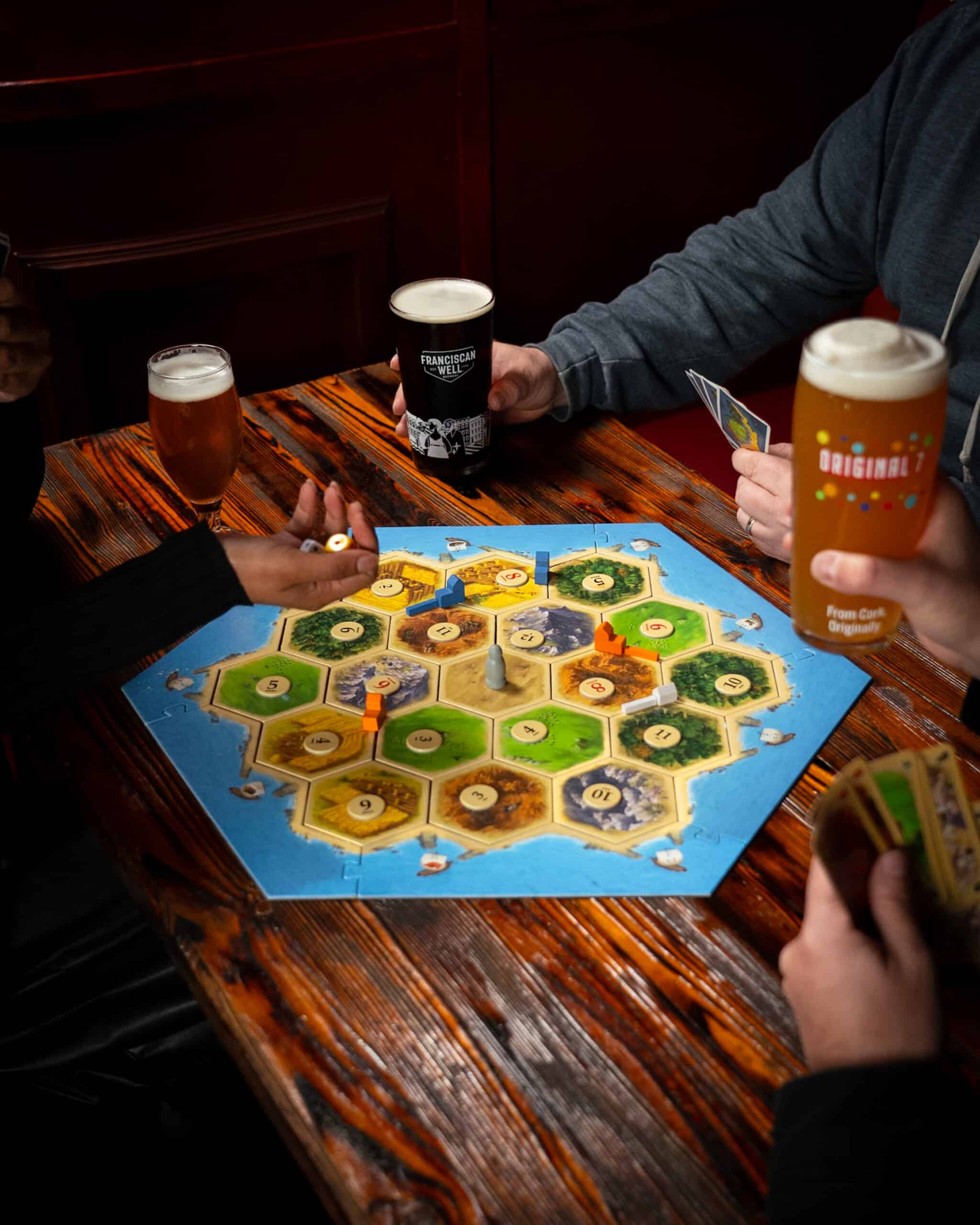 Friends sitting together, playing a board game, with laughter and excitement evident in their expressions.